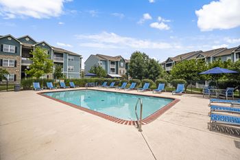 A swimming pool surrounded by blue lounge chairs and umbrellas. at Aventura at Richmond, St. Peters, 63376