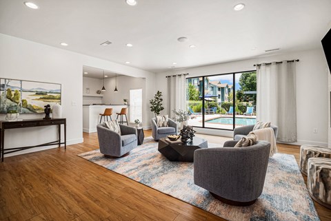 A living room with a large painting on the wall and a view of a pool outside.