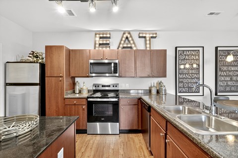 A kitchen with wooden cabinets and a stainless steel refrigerator.