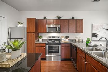 A kitchen with wooden cabinets and a black countertop. at Aventura at Richmond, St. Peters, 63376