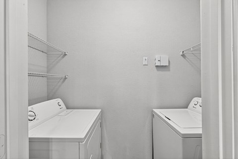 A laundry room with two washing machines and a shelf.