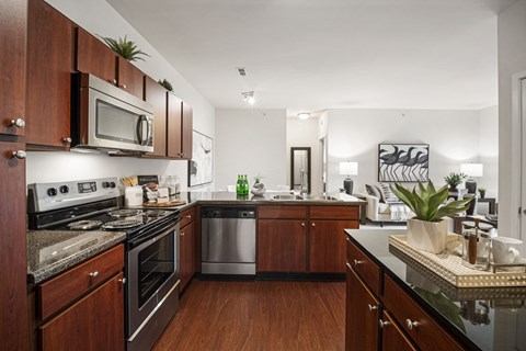 A kitchen with dark wood cabinets and a black counter top.