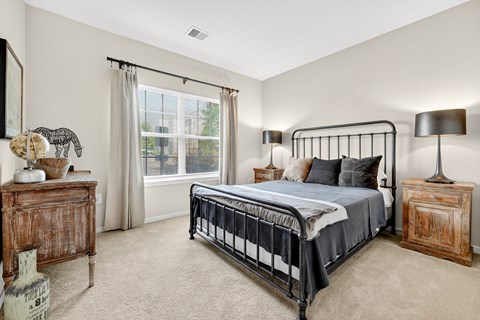 A bedroom with a large bed, a wooden dresser, and a lamp.