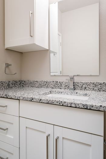 A white kitchen with a granite counter top and cabinets.