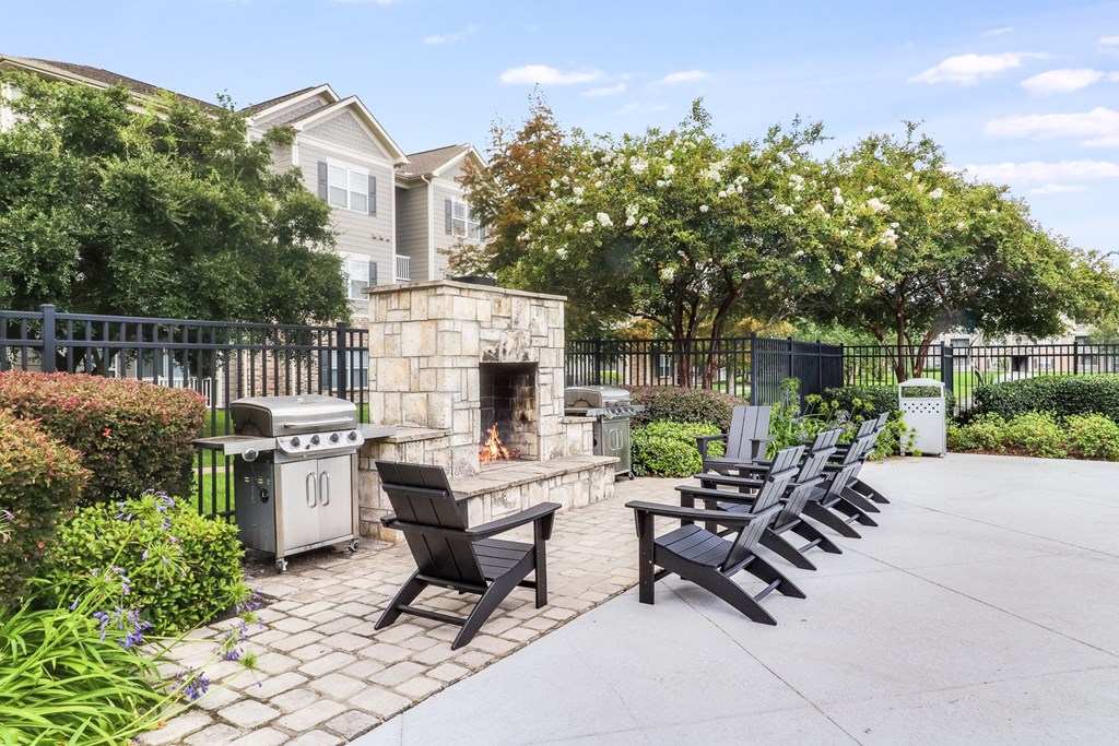an outdoor patio with a stone fireplace and lounge chairs  at Plantation Crossing, Lafayette, LA