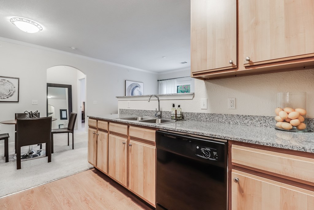 A kitchen with wooden cabinets and a black dishwasher.Plantation Crossing, Lafayette, LA, 70508