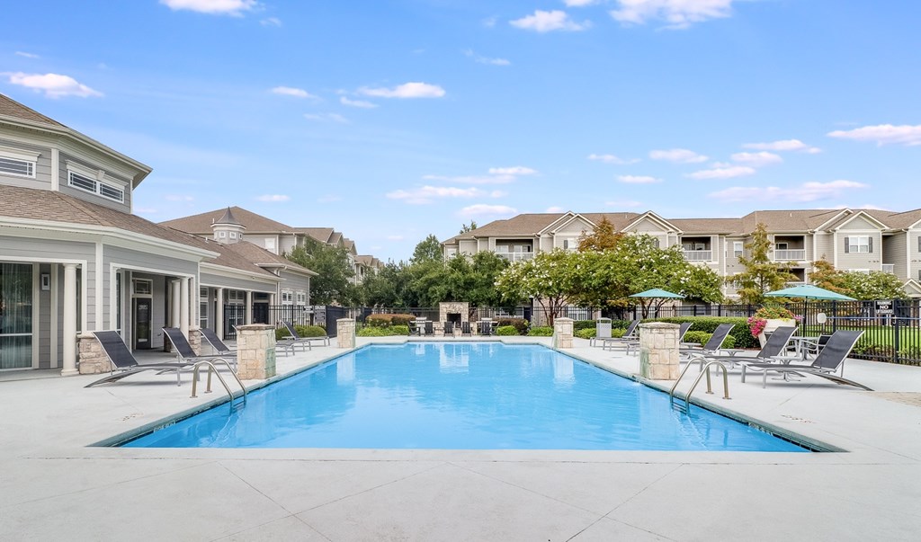 A large swimming pool surrounded by lounge chairs and umbrellas in a residential area, Plantation Crossing, Lafayette, LA, 70508