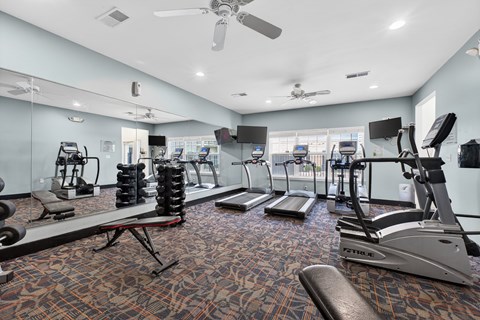 A gym with a variety of equipment including treadmills, weights, and exercise machines.