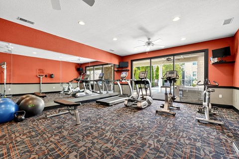 A gym with a variety of equipment including treadmills, weights, and exercise machines.
