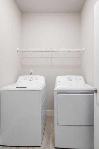 Two white front loading washing machines in a small laundry room.