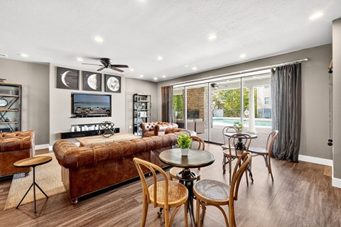 A living room with a brown couch, a television, and a ceiling fan.