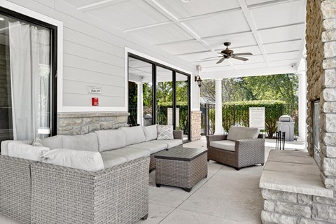 A patio with a white couch and a fan.