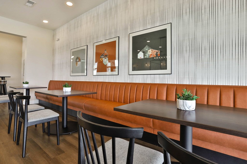 a dining room with orange booths and black tables and chairs at Aventura at Hawk Ridge, Lake St Louis, MO 63367
