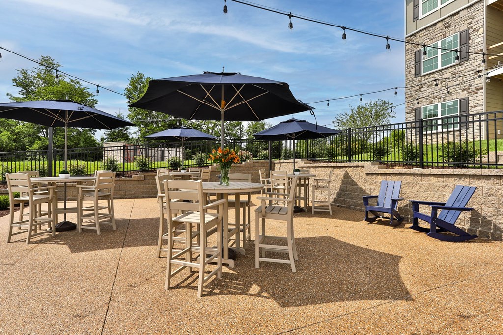 a patio with tables and chairs and umbrellas  at Aventura at Hawk Ridge, Lake St Louis, Missouri