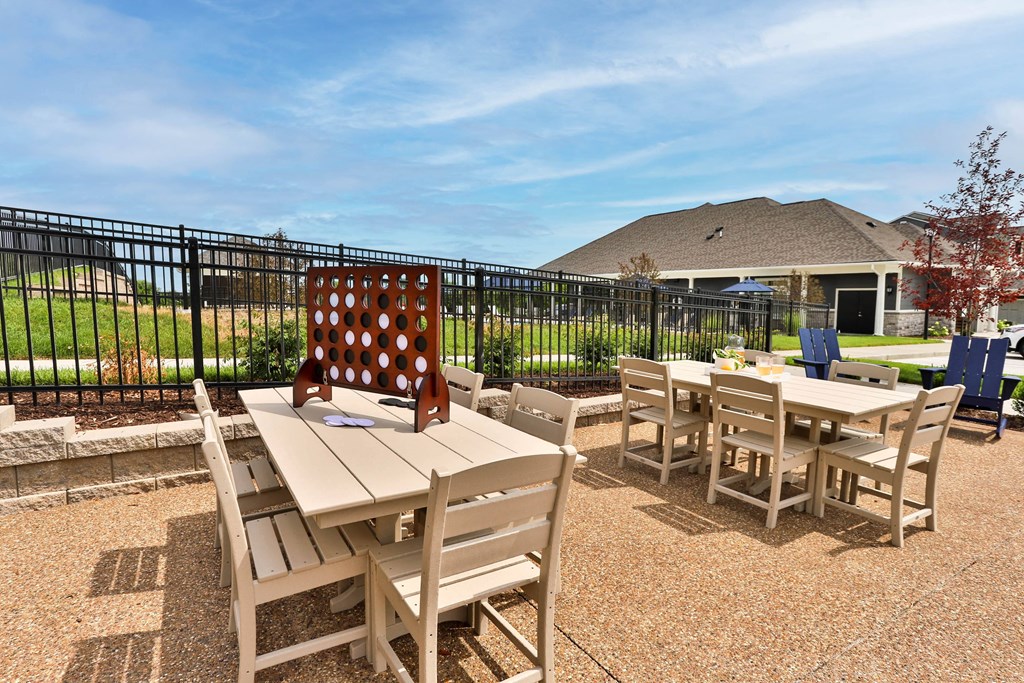 a patio with tables and chairs and a house in the background  at Aventura at Hawk Ridge, Missouri
