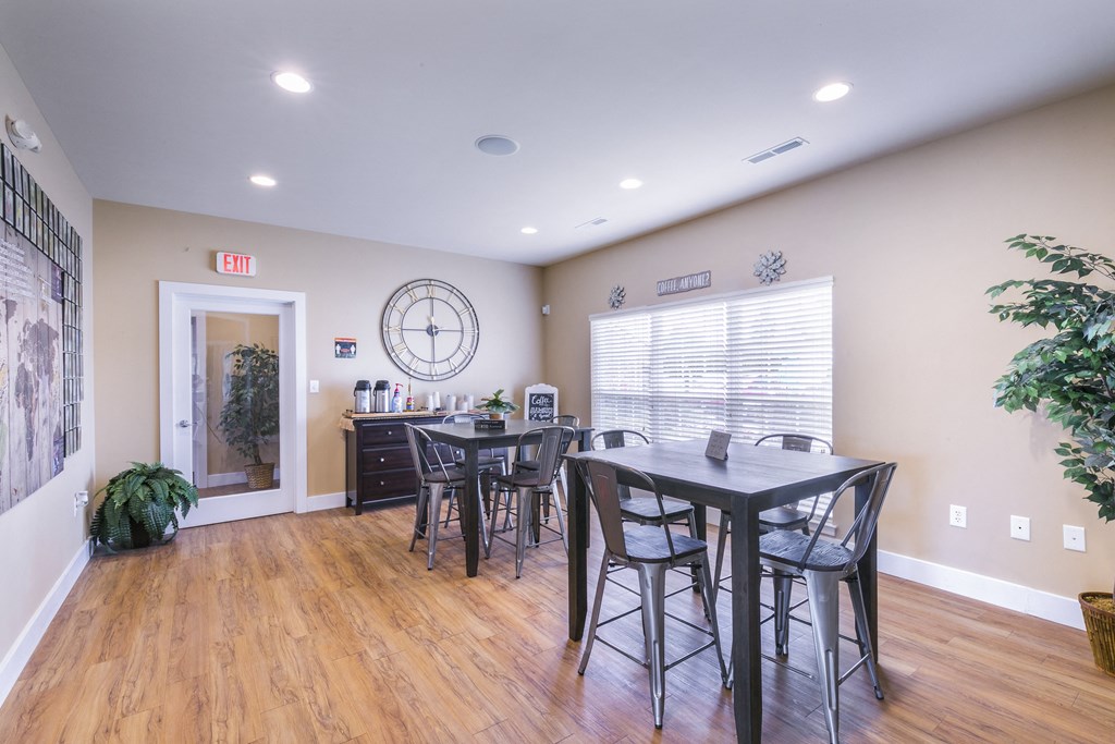 a dining area with a table and chairs and a large clock on the wall  at Aventura at Richmond, Missouri