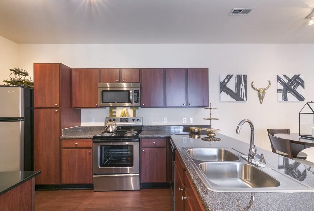 a kitchen with stainless steel appliances and wooden cabinets  at Aventura at Richmond, St. Peters