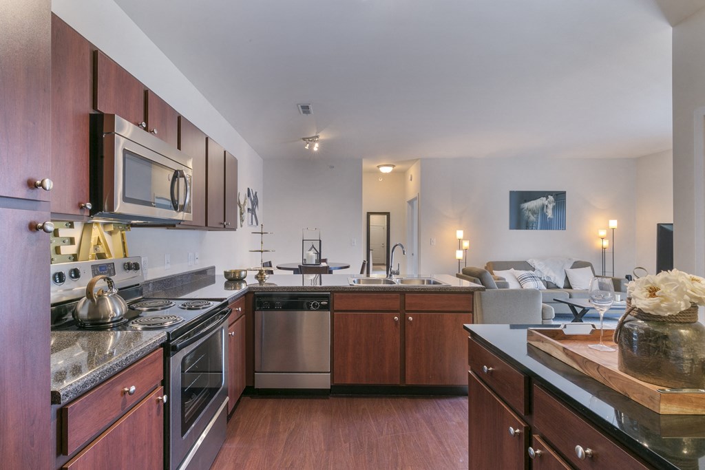 a kitchen with a stove top oven next to a sink  at Aventura at Richmond, Missouri