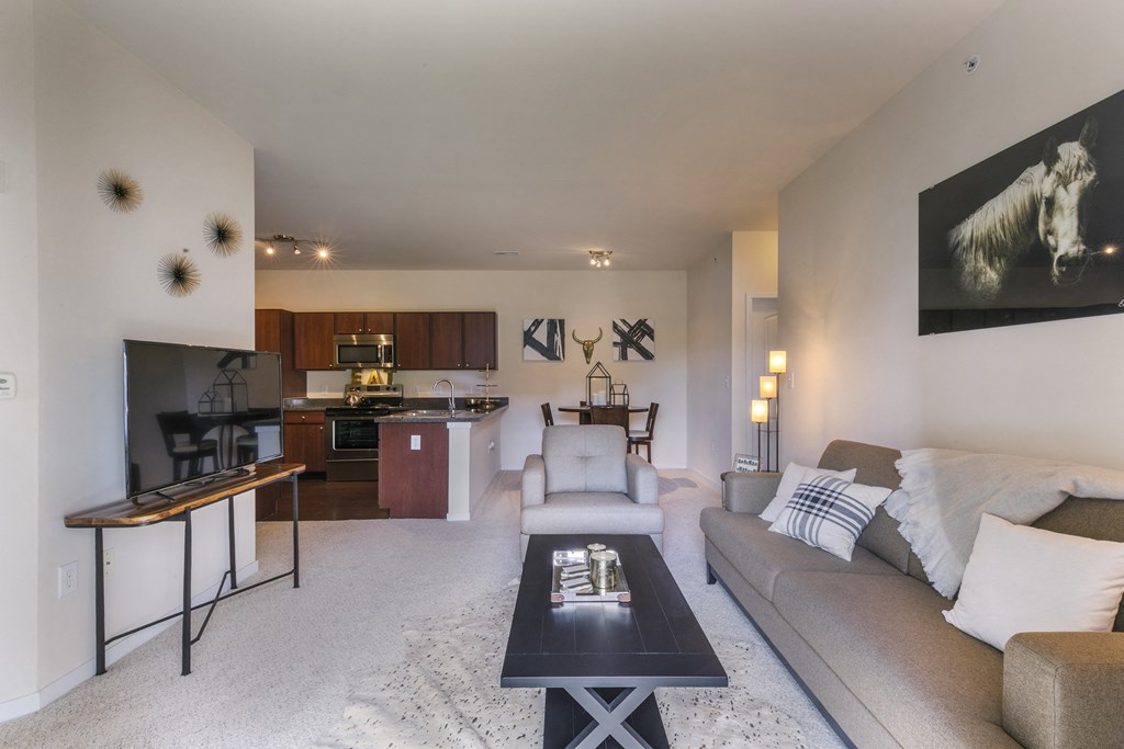 a living room with a couch a table and a kitchen in the background  at Aventura at Richmond, Missouri, 63376