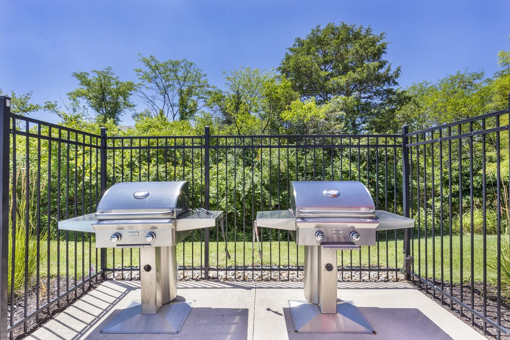two bbqs in front of a fence with trees at Aventura at Towne Centre, Ellisville, Missouri