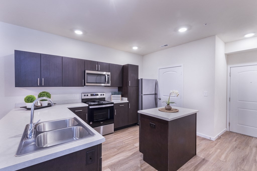 a kitchen with white counter tops and dark cabinets and stainless steel appliances at Aventura at Towne Centre, Missouri