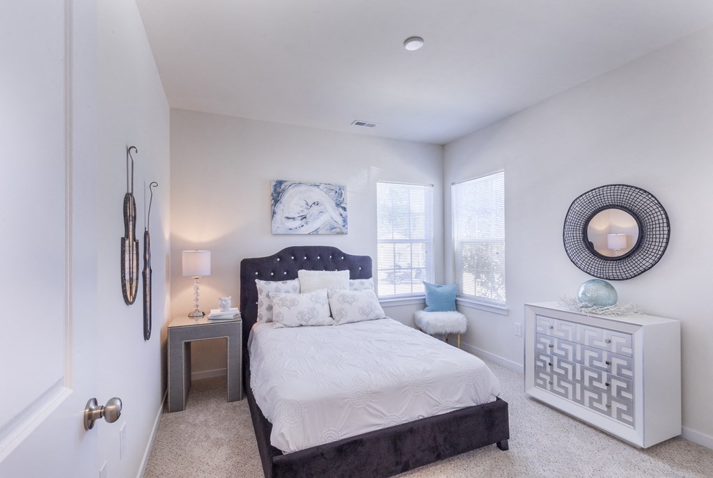 a bedroom with a bed and two windows at Aventura at Towne Centre, Ellisville