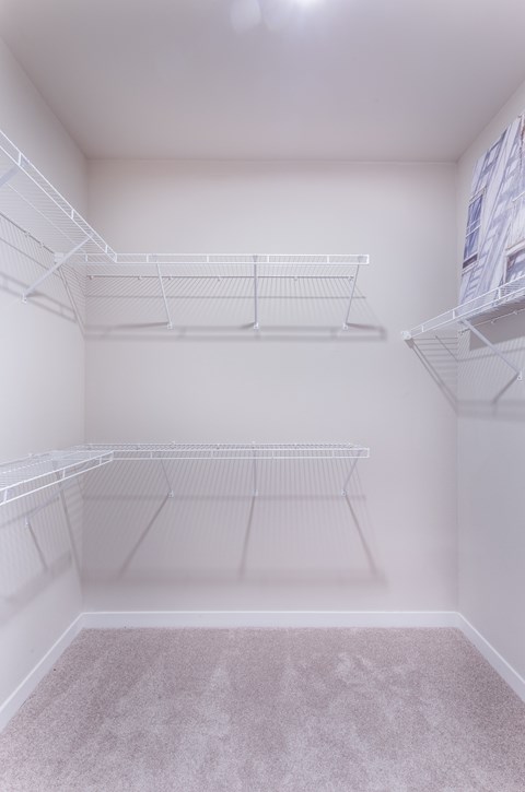 the walk in closet of a studio apartment with white shelves and a mirrored floor at Aventura at Wild Horse Creek, Chesterfield