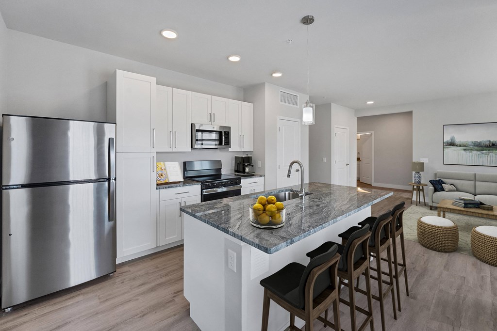 a kitchen with white cabinetry and a large island with a granite countertop  at The Edison at Chapel Hills, Colorado, 80920