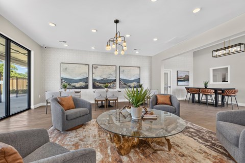 A living room with a glass table and grey couches.