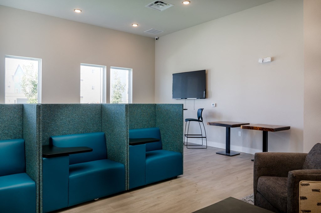 a seating area with blue chairs and a table with a chair and a tv on the wall at The Edison at Blue Springs, Blue Springs, MO 64014