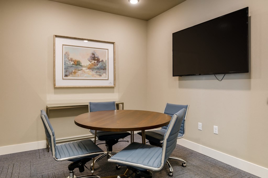 a meeting room with a table and chairs and a flat screen tv at The Edison at Blue Springs, Blue Springs