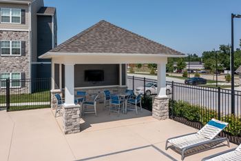A gazebo with a stone pillar and a bench is in the foreground of a residential area at Aventura at Wentzville I & II Apartments, Wentzville, Missouri