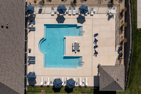 An aerial view of a pool surrounded by lounge chairs and umbrellas.
