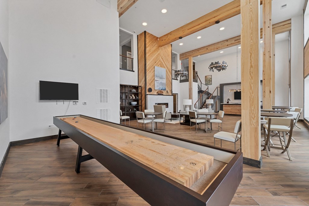 a large wooden ping pong table in a large room with a living room in the background  at The Edison at Chapel Hills, Colorado