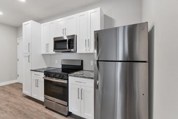 an empty kitchen with stainless steel appliances and white cabinets