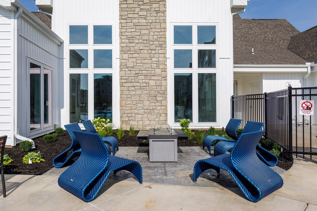 a patio with blue chairs and a fire pit in front of a building at The Edison at Blue Springs, Blue Springs, 64014