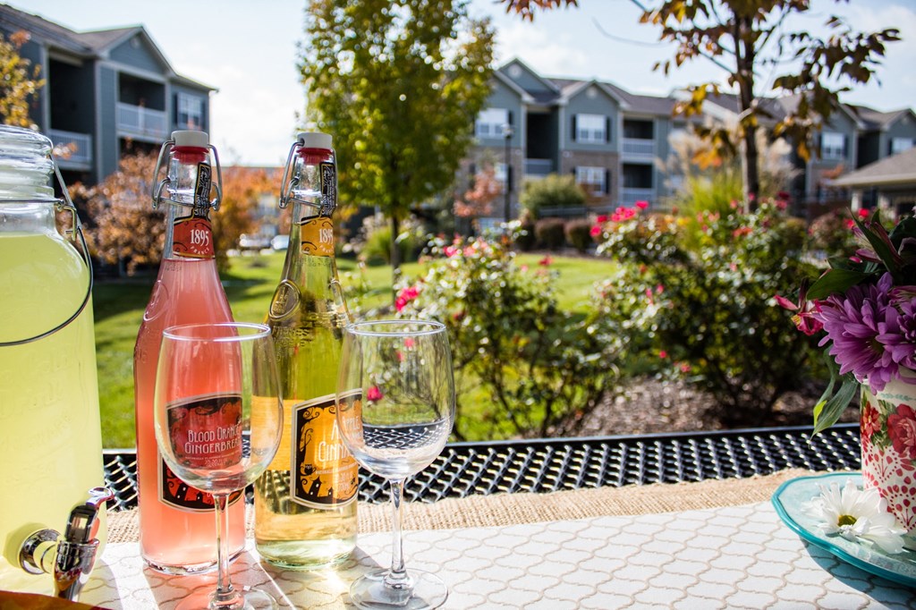 a bottle of wine and glasses on a patio table at Aventura at Richmond, St. Peters, MO