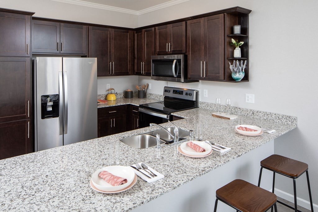 a kitchen with granite countertops and stainless steel appliances at The Edison at Rice Creek, Shoreview, MN