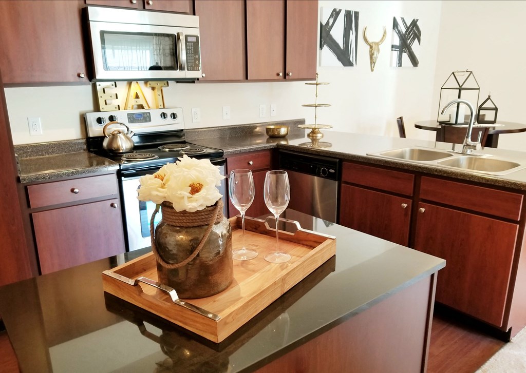 a kitchen with a wooden cutting board with a vase and glasses on a counter at Aventura at Richmond, Missouri, 63376