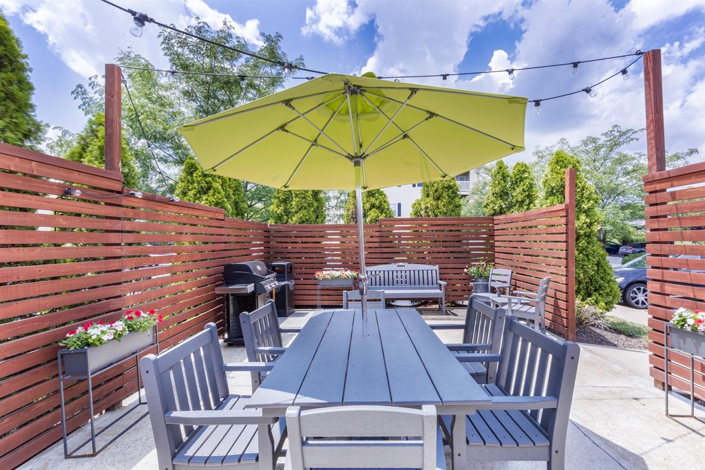 a patio with tables and chairs and a yellow umbrella