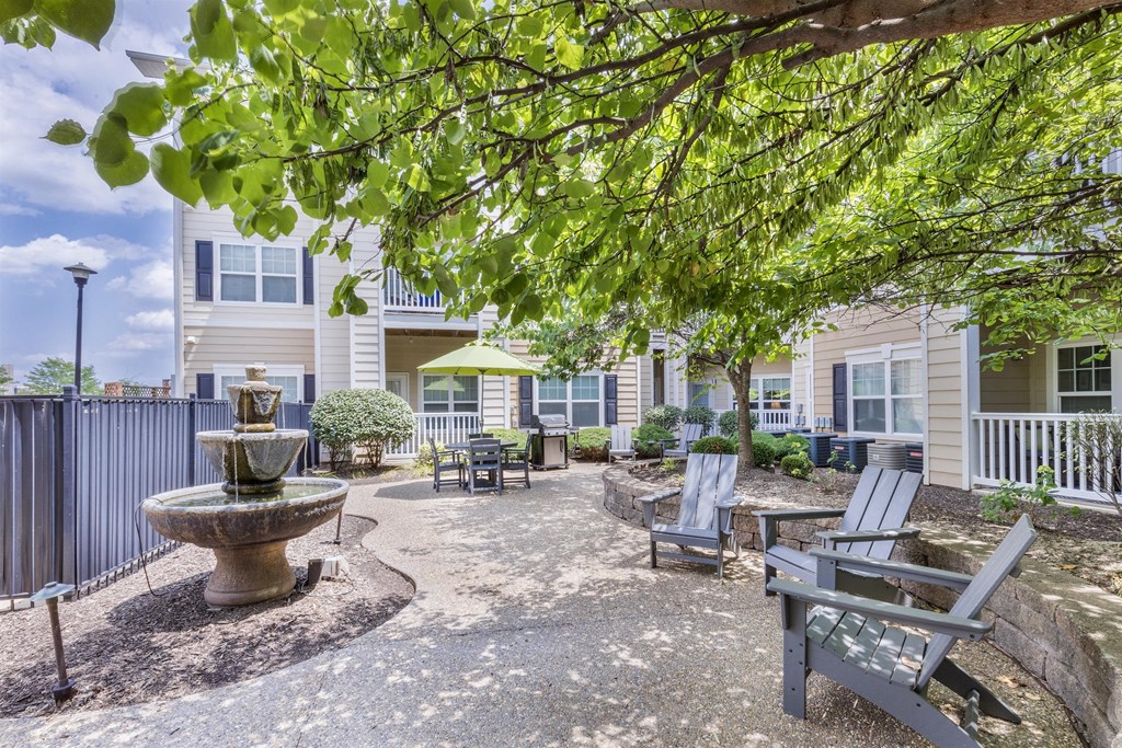 a courtyard with a fountain and benches in front of a building