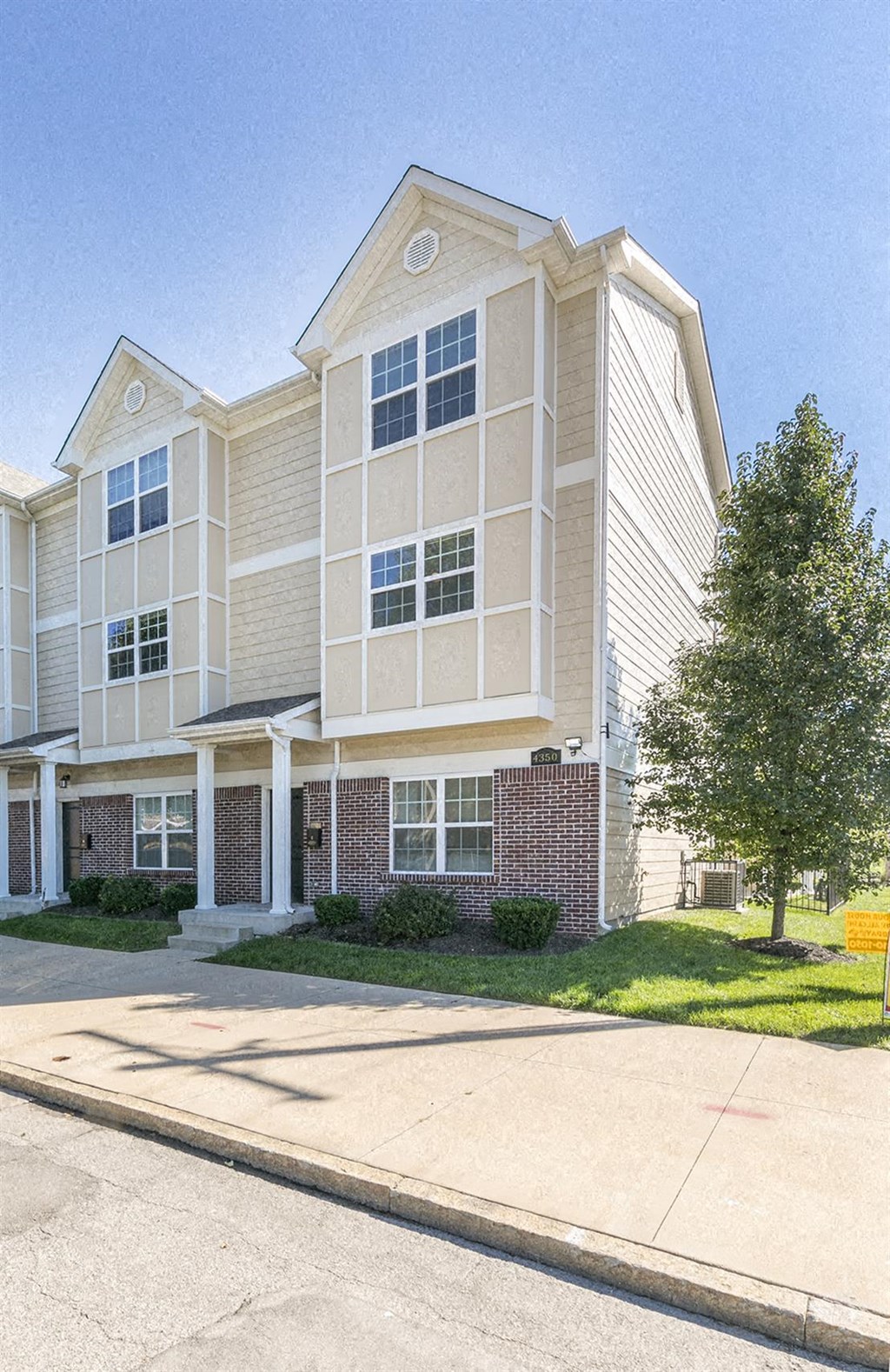 an apartment building with a driveway and a tree in front of it
