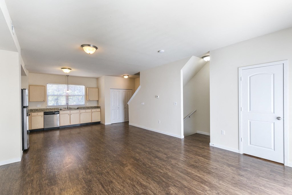 an empty living room and kitchen with wood floors
