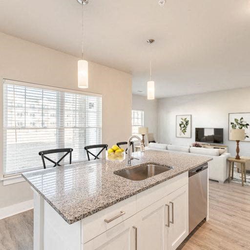 a kitchen island with a sink and chairs at The Edison at Madison, Madison, 35757
