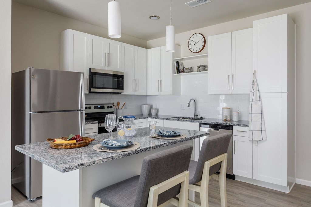 a kitchen with a large center island with a granite countertop at The Edison at Blue Springs, Blue Springs, 64014