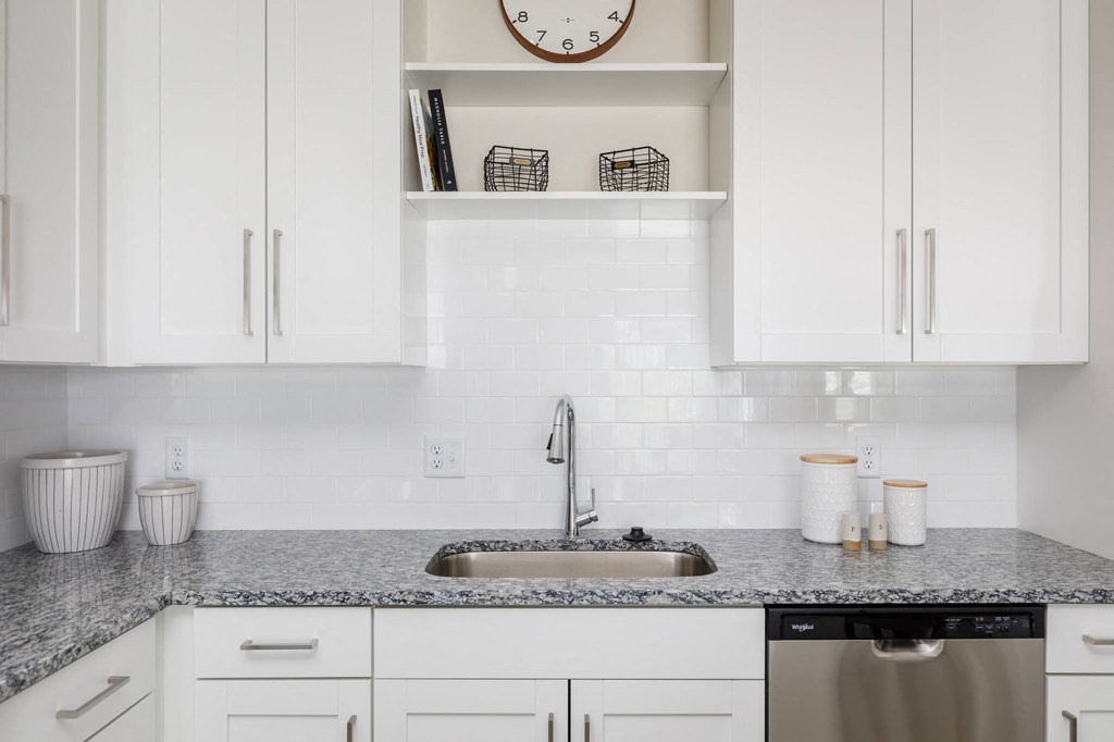 a kitchen with white cabinets and granite countertops at The Edison at Blue Springs, Blue Springs, MO 64014