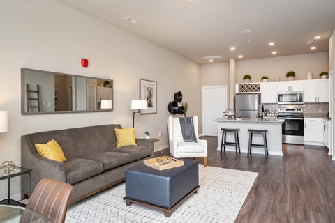 a living room with a couch and a chair in front of a kitchen