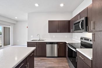 A modern kitchen with dark wood cabinets and stainless steel appliances at Aventura at Wentzville I & II Apartments, Wentzville, MO