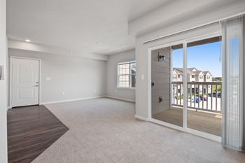 A spacious living room with a sliding glass door leading to a balcony at Aventura at Wentzville I & II Apartments, Wentzville, 63385