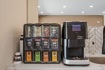 A coffee machine is on a counter next to a box of coffee pods at Aventura at Wentzville I & II Apartments, Wentzville